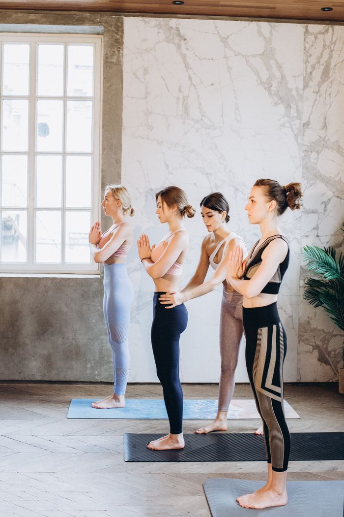 Women standing in yoga poses in a bright indoor studio, enhancing mindfulness and well-being.