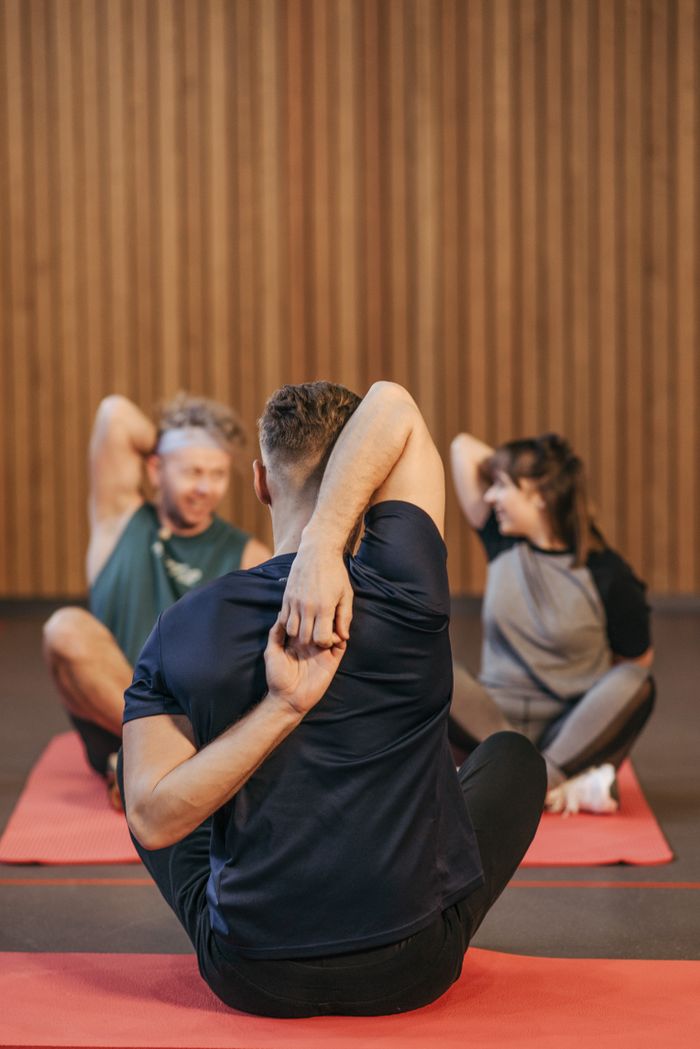 our-story Adults in activewear practicing yoga and stretching indoors on mats.