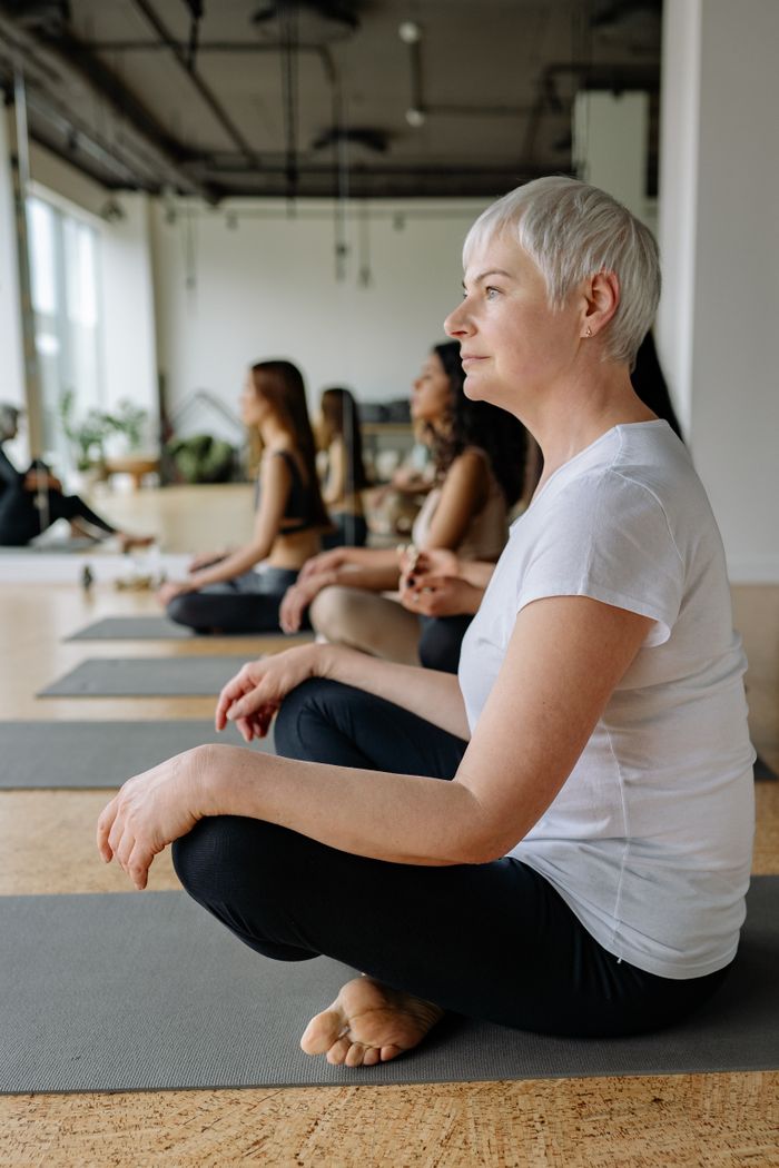 who-we-are Adults in a modern studio practicing yoga and meditation for wellness and relaxation.